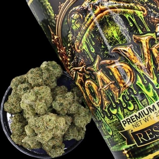 Toad Venom Reserve Batch 28g jar showing dripping green toad artwork next to a bowl of dense frosty cannabis nugs